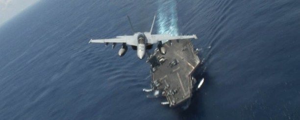 An F/A 18 Hornet over the USS Nimitz